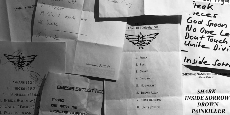Ein Bild von einer Wand, an die verschiedene Setlists von Auftritten der Band angeheftet wurden.